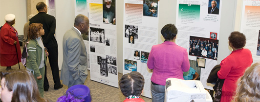 A group of people reads a series of large panels at an NLM traveling exhibition.