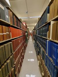 Long rows of bookshelves on both sides of a narrow corridor in Countway Library.