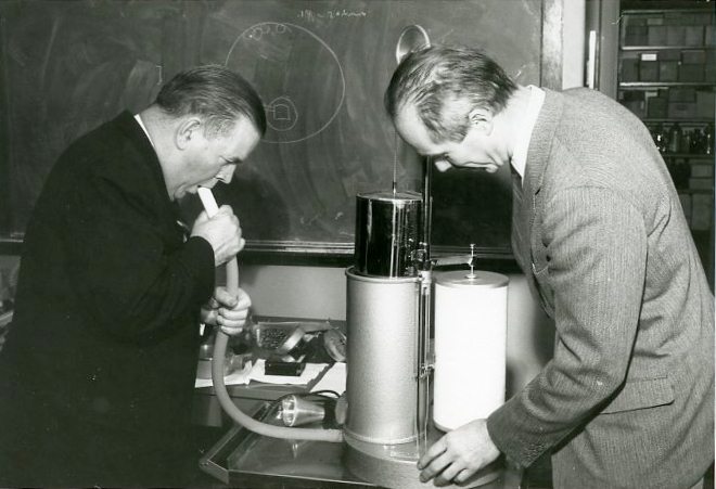 Two people measure respiration using a spirometer in 1961.